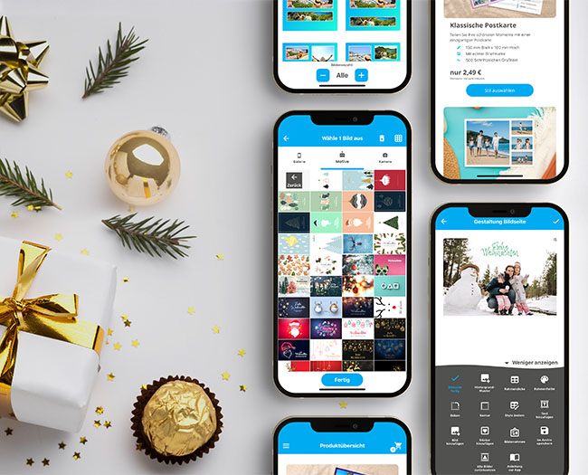 iPhones mit der Urlaubsgruss Postkarten App liegen auf einem Tisch mit Weihnachtsschmuck.